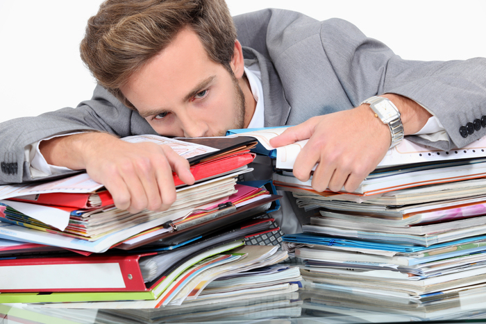 Man drowning in stacks of paperwork
